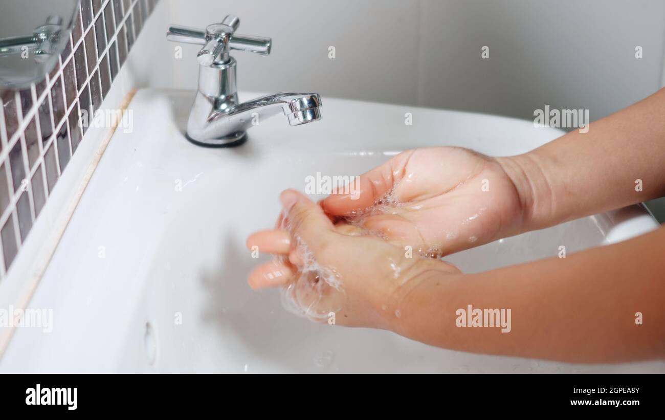 Closeup young woman hands using soap and washing hands under the water ...