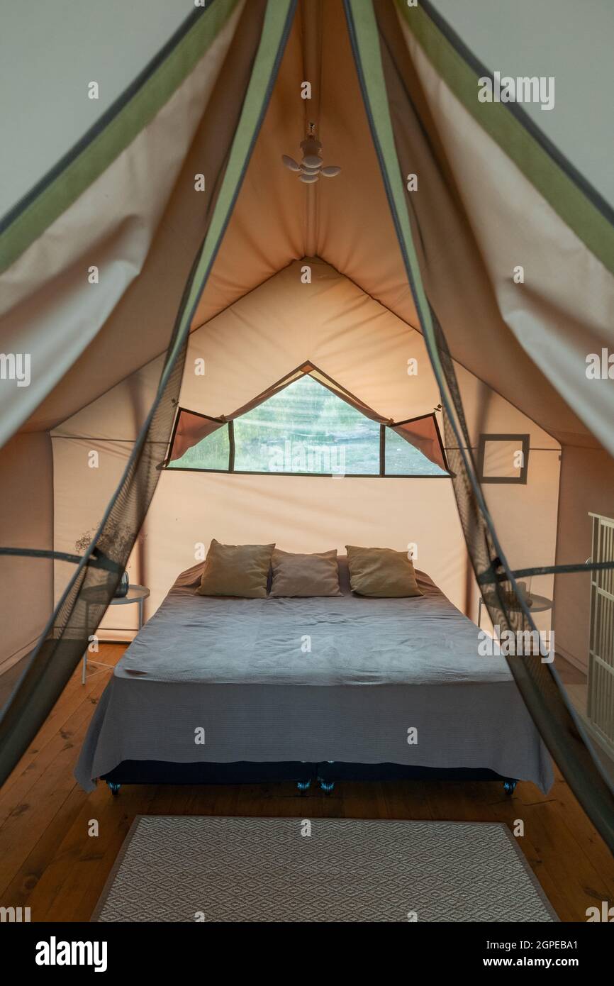 Bedroom with large bed under window and rug on wooden floor inside