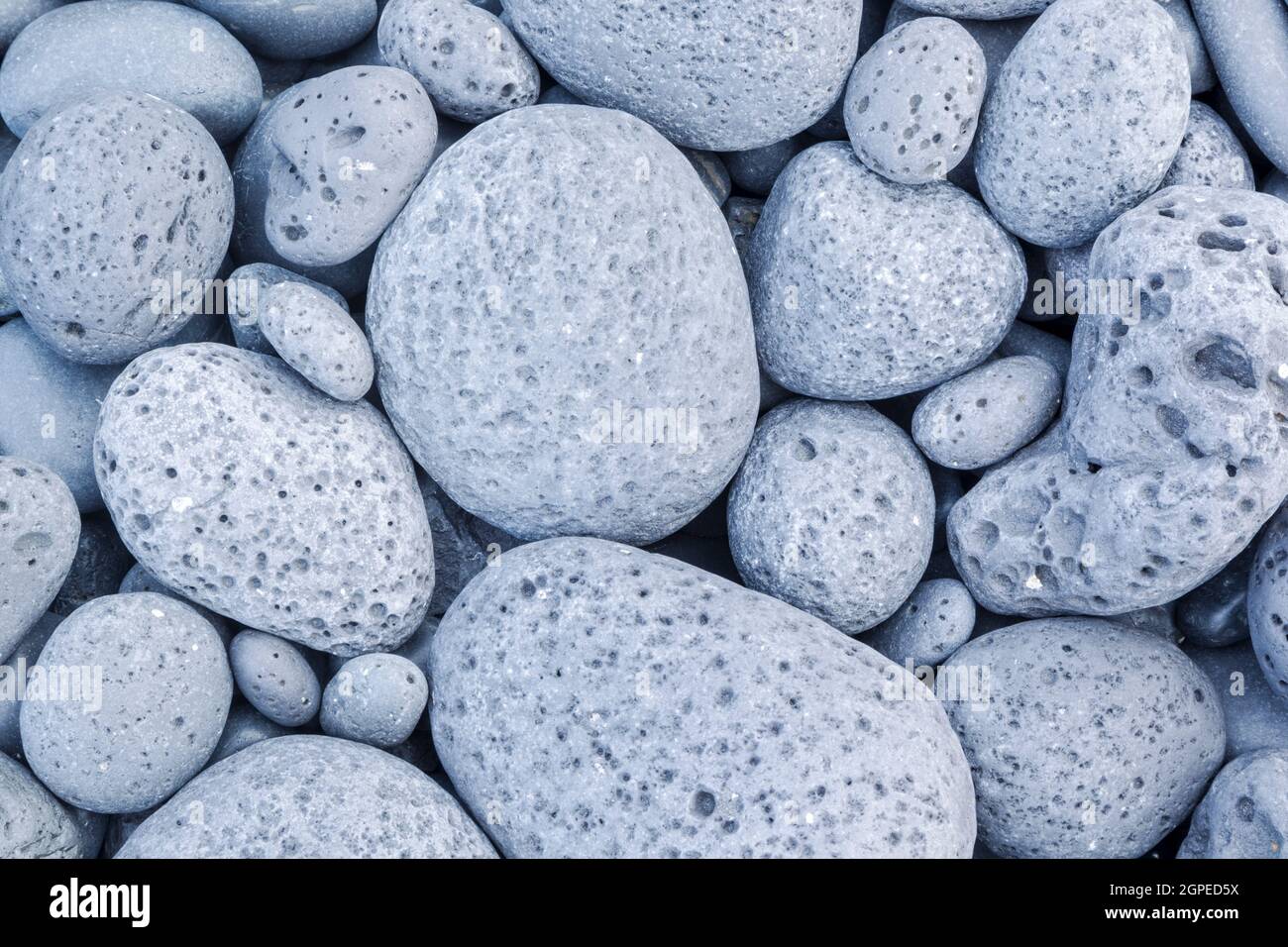 Pale grey beach stones battered and worn by the sea Stock Photo