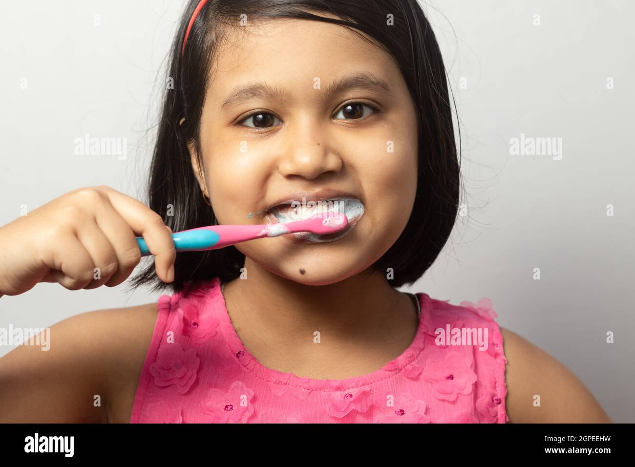 Head shot of an Indian girl child brushing teeth with toothbrush on ...