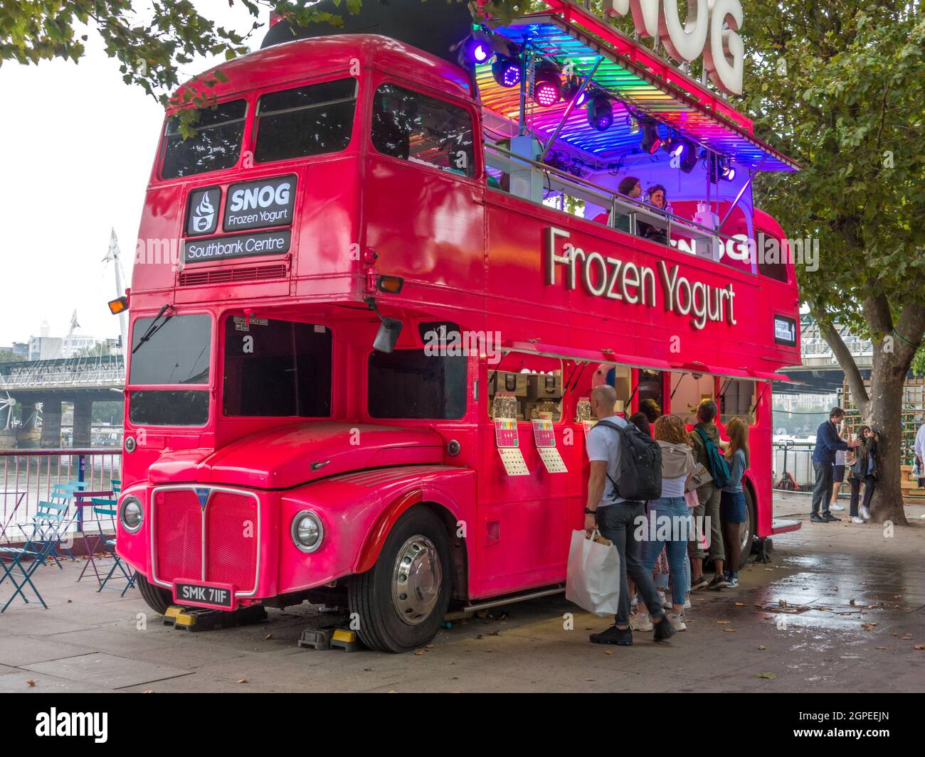 A double decker bus converted to a frozen yoghurt takeway, parked and serving passing customers at South Bank, London, England, UK. Stock Photo