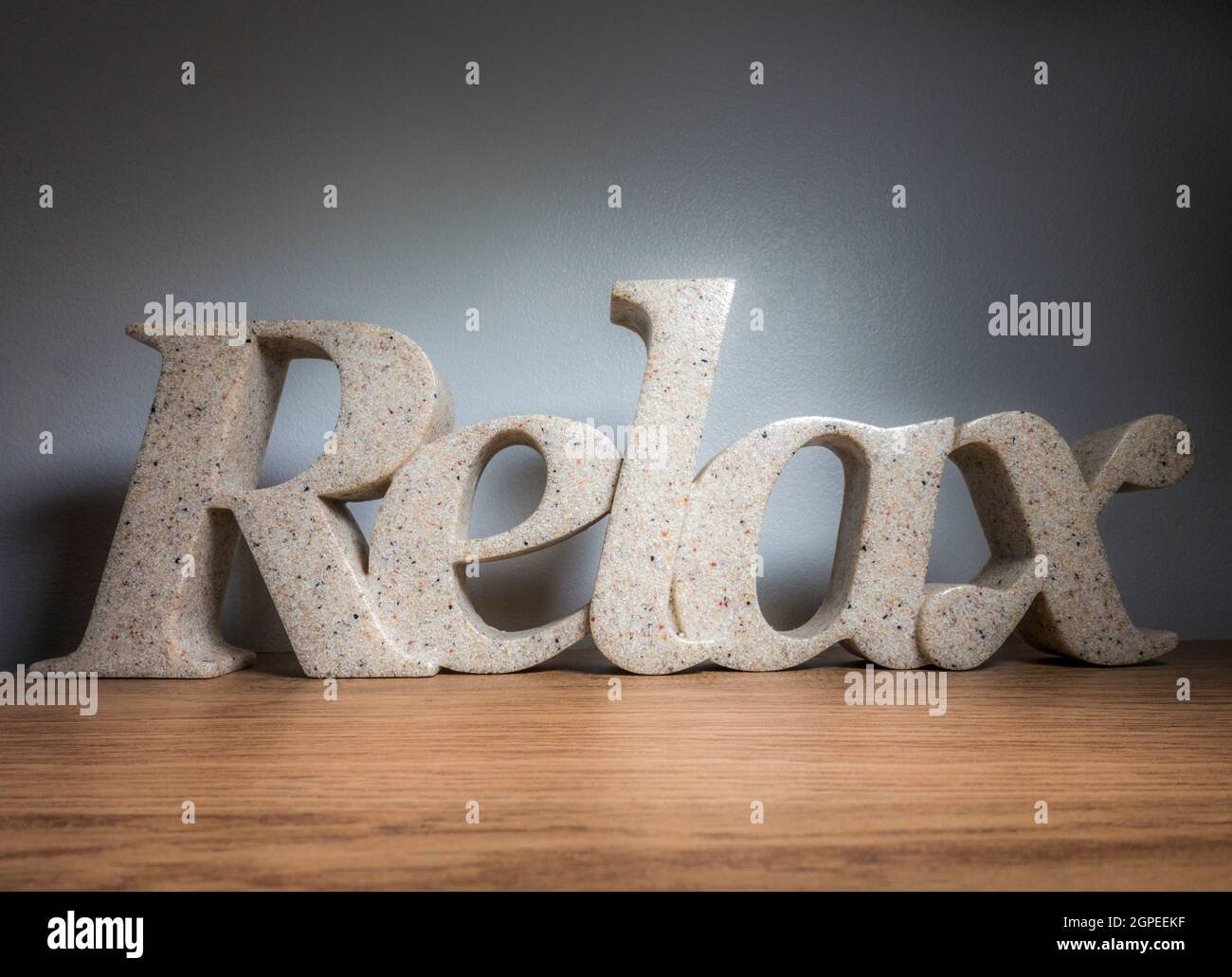 Closeup POV shot of a stone ornament spelling the word Relax, standing on a shelf against an interior wall. Relaxation at home concept. Stock Photo