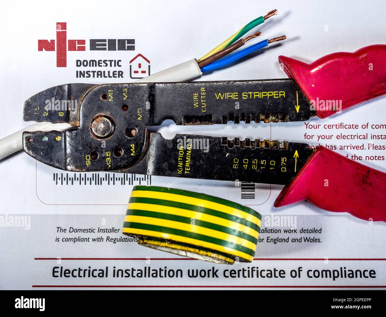 NICEIC compliance certificate – National Inspection Council for Electrical Installation Contracting - with wire strippers, cable and tape on top. Stock Photo