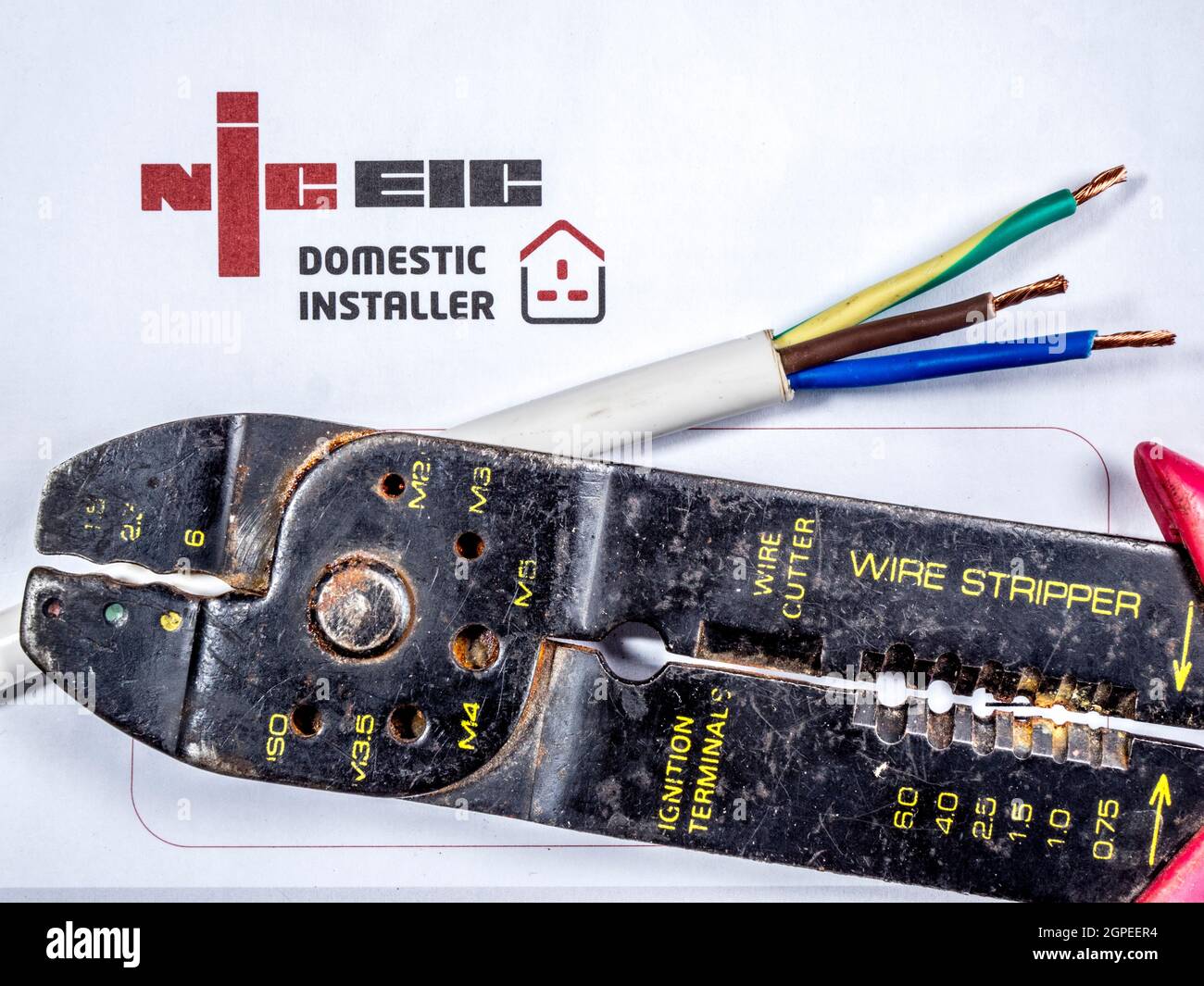 NICEIC logo – National Inspection Council for Electrical Installation Contracting - with wire strippers and a cable with brown, green and blue wires. Stock Photo