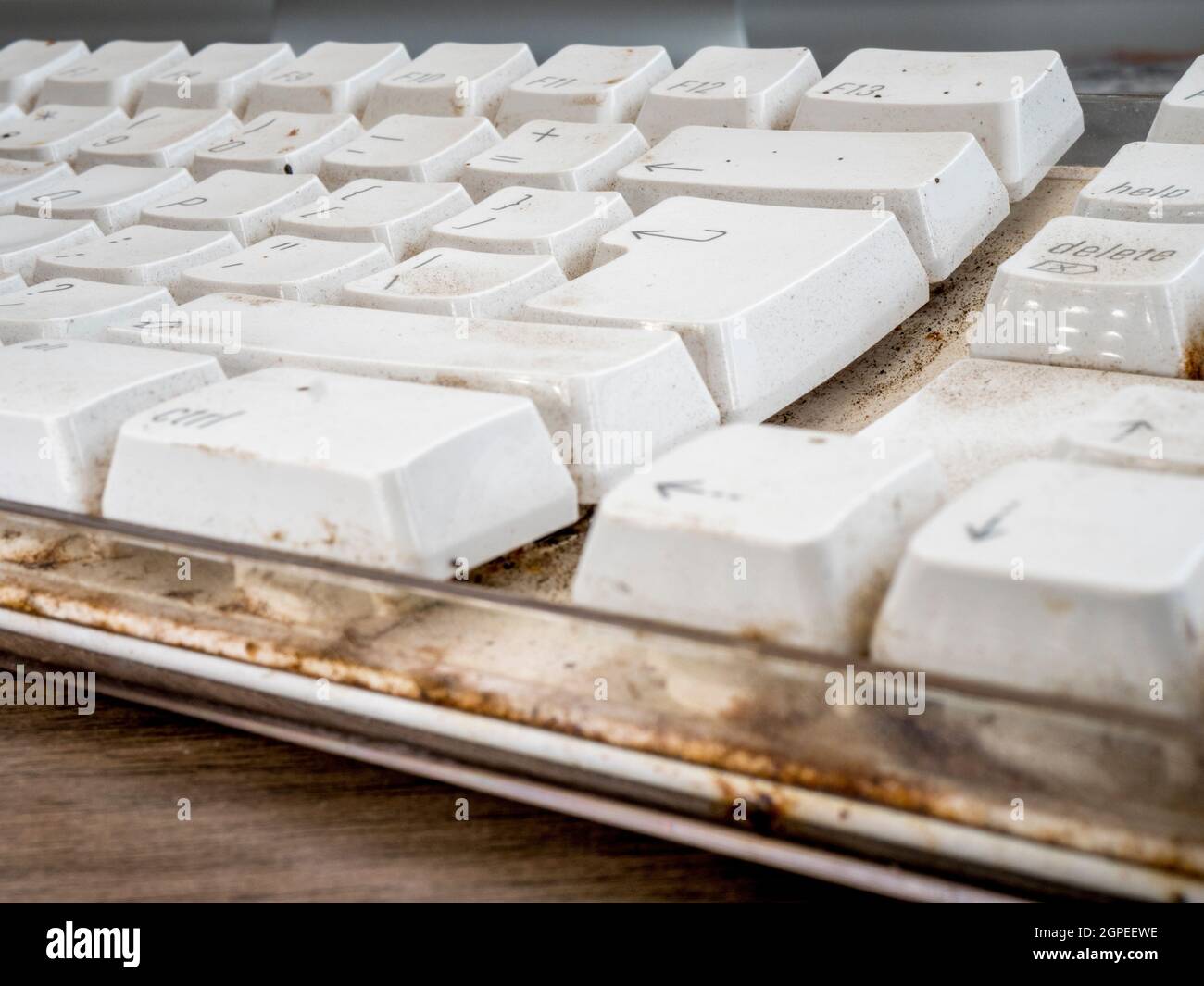 Closeup POV shot of a filthy dirty white computer keyboard on an office desk. Stock Photo