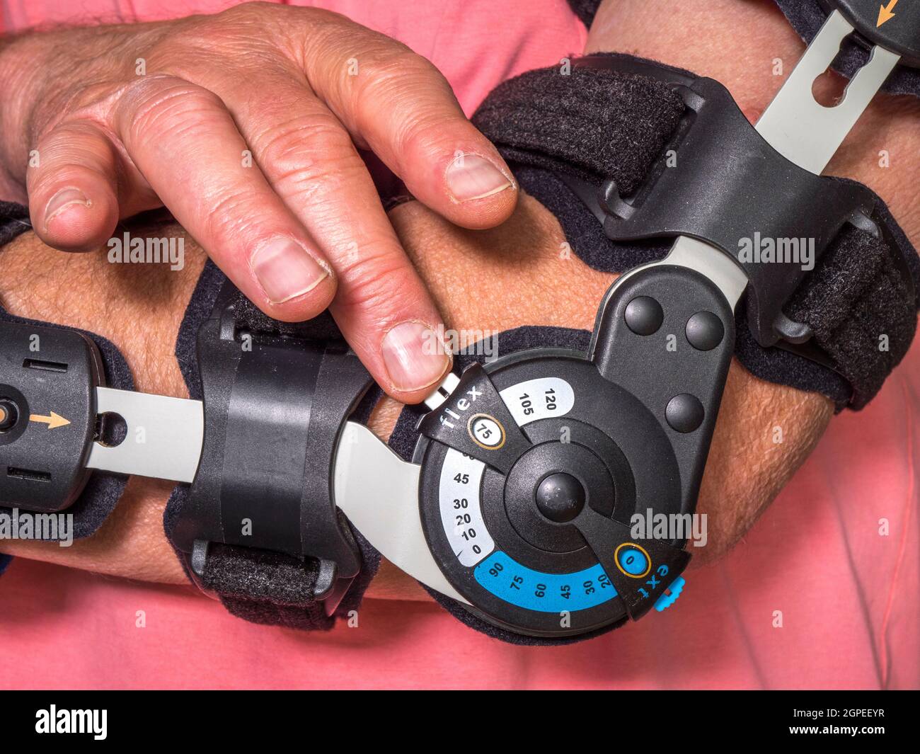 Closeup POV shot of an elderly man adjusting a fitted arm brace, for a greater range / degree of elbow movement. Stock Photo