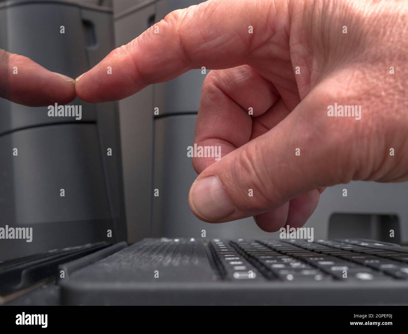 Closeup POV shot of a man’s finger tapping / touching a tablet screen / display, next to a portable keyboard, in front of a printer. Stock Photo