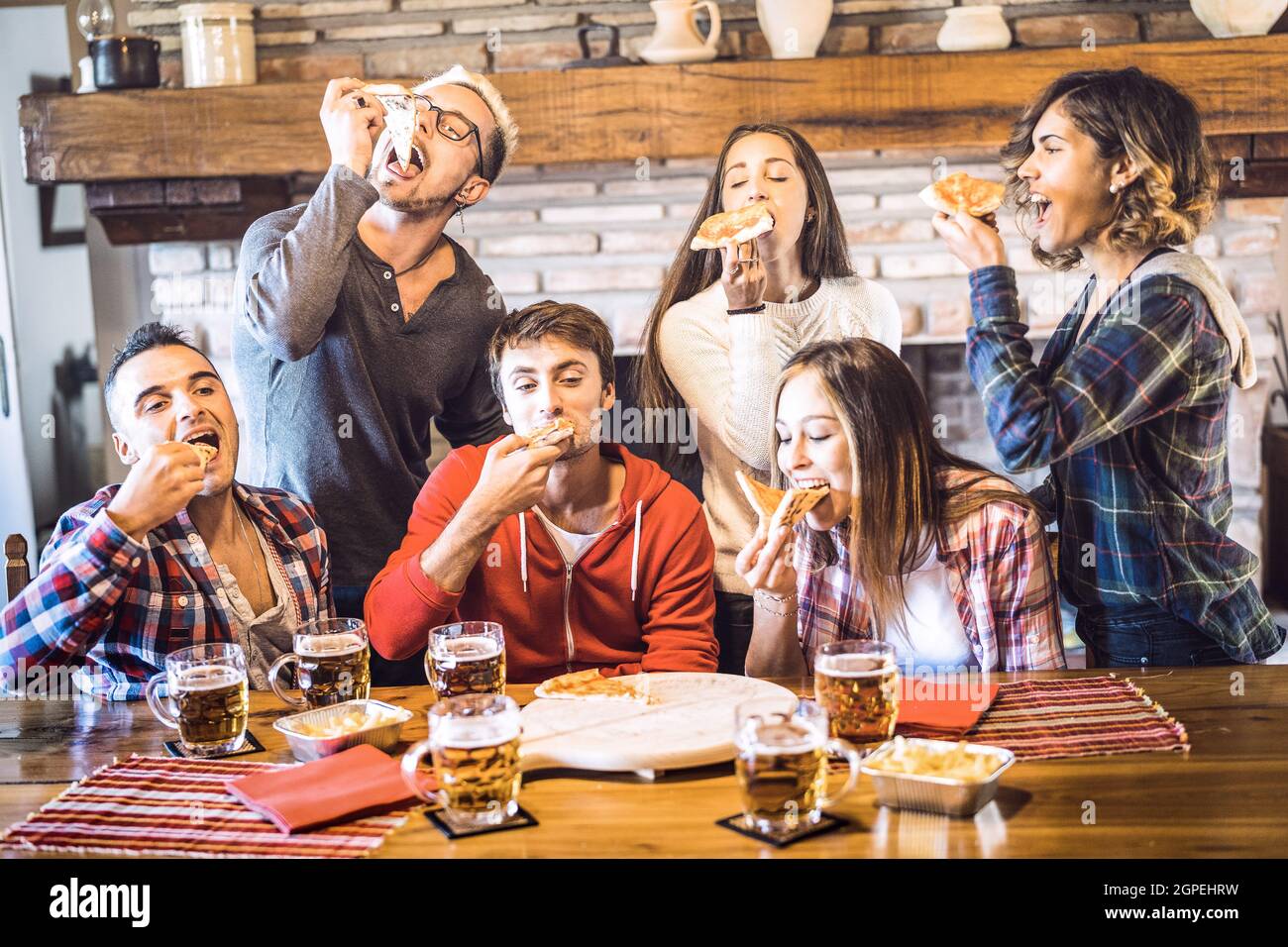 Happy friends group eating pizza at chalet restaurant house - Friendship concept with young people enjoying time together and having genuine fun Stock Photo