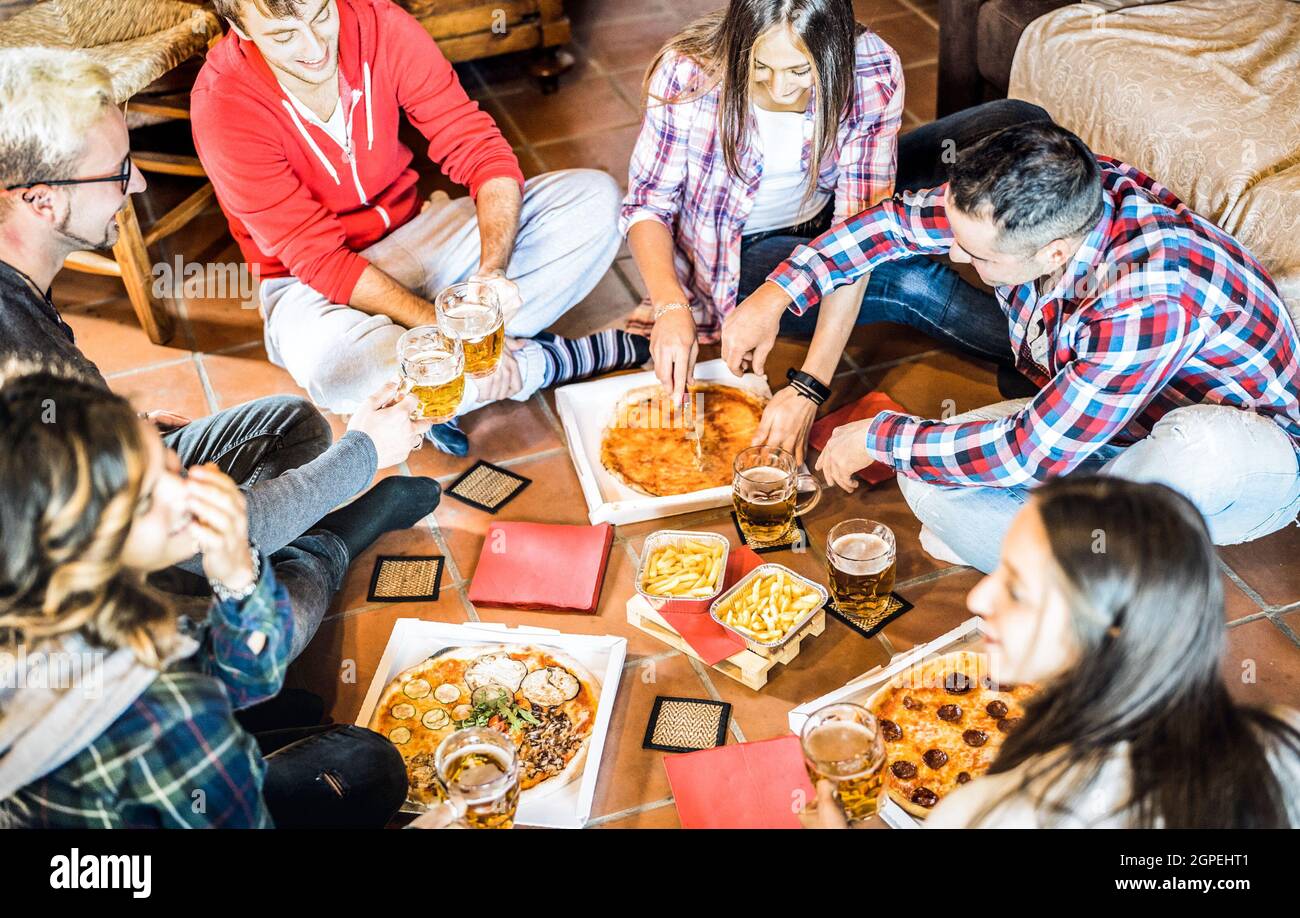 Happy friends eating take away pizza at home after work - Friendship concept with young people enjoying time together and having genuine fun Stock Photo