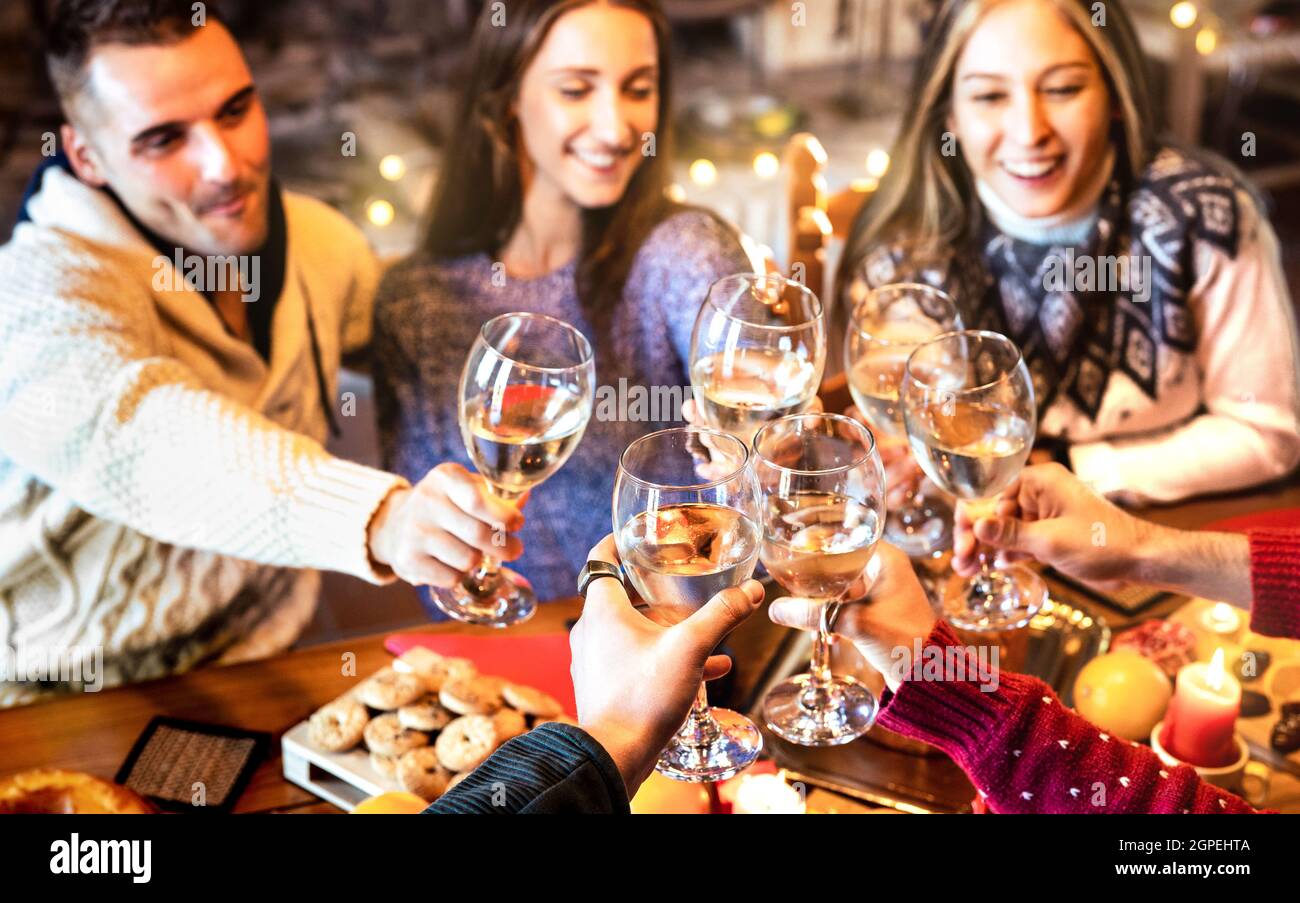 People group celebrating Christmas toasting champagne wine at home dinner party - Winter holiday concept with young friends enjoying time together Stock Photo
