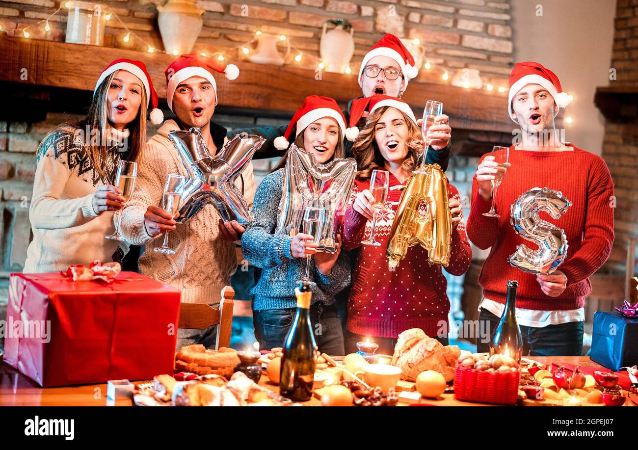 Friends group with santa hat celebrating Christmas time with champagne and sweets food at dinner party - Winter holiday concept with people together Stock Photo