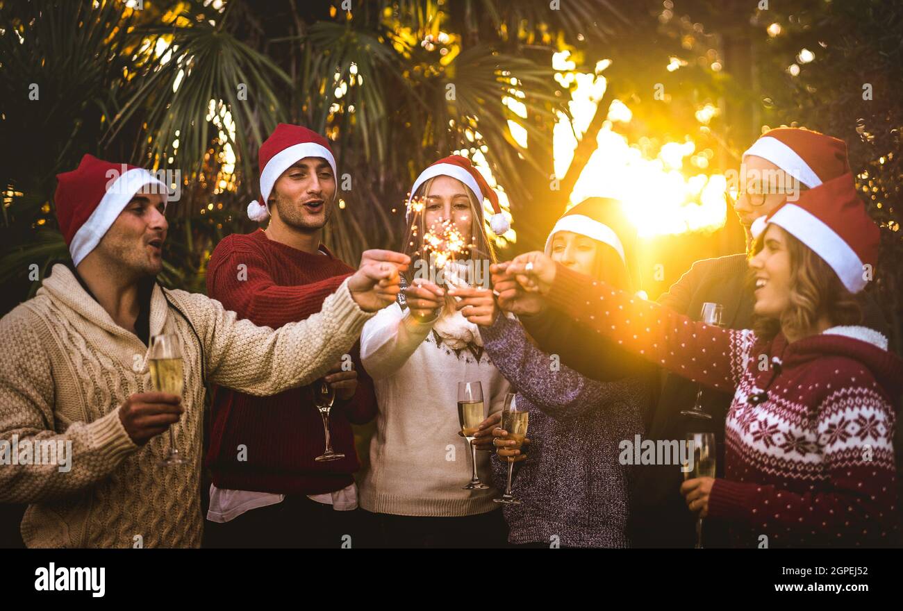 Friends group with santa hats celebrating Christmas with champagne wine toast outdoors - Tropical holidays concept with young people enjoying time Stock Photo