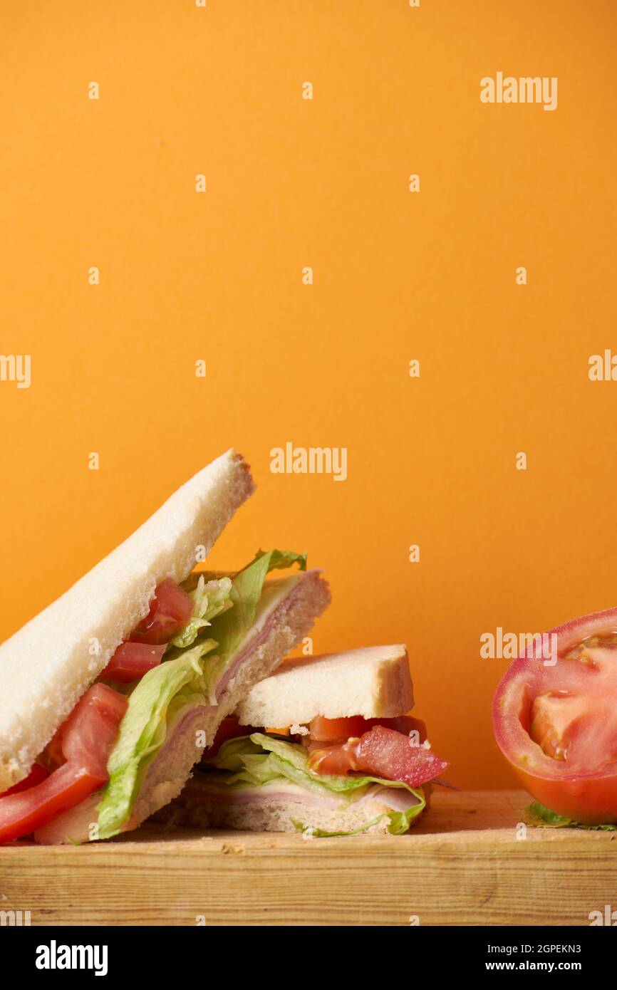 Healthy ham and cheese sandwich with tomato and lettuce in orange background Stock Photo