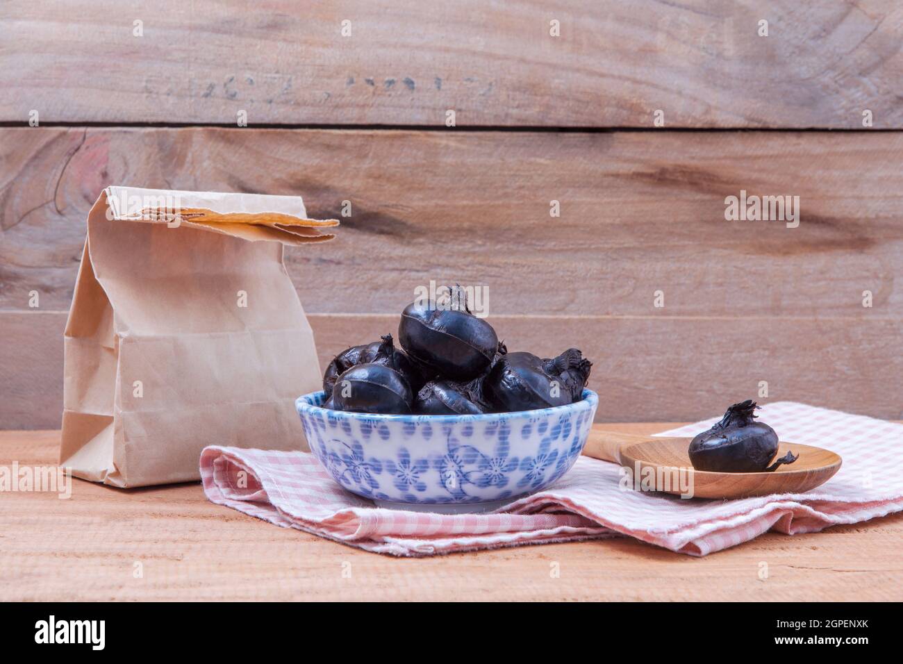 Chinese water chestnut ,water nut or Matai roots in the bowl and paper bag on rustic old wooden background. Stock Photo