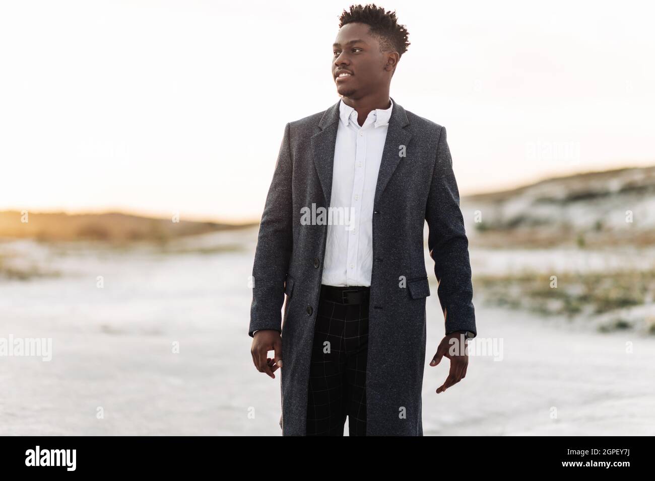 Handsome stylish black man in classic white shirt, trousers and coat,  posing outdoors at sunset, successful man, fashion concept, men's fashion,  class Stock Photo - Alamy