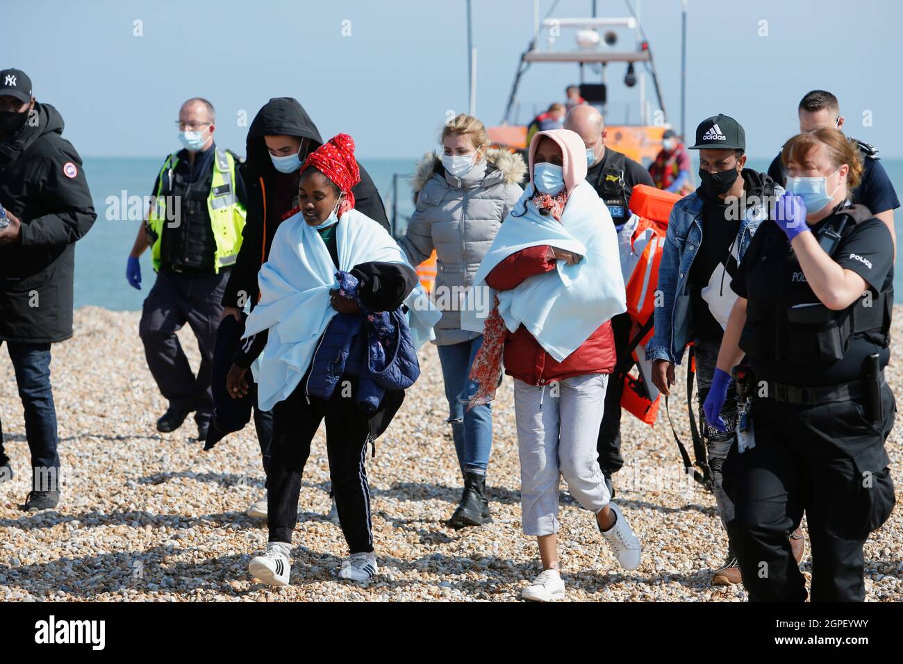 England, Kent, Dungeness, Immigration officers escorting recently landed migrants to be processed. Stock Photo