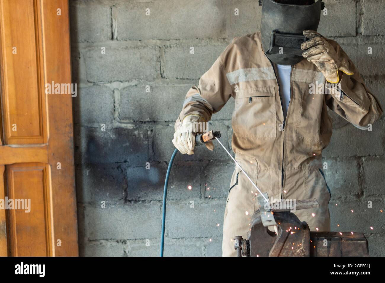 Unrecognizable welder wearing special protective helmet welding metal details using torch Stock Photo