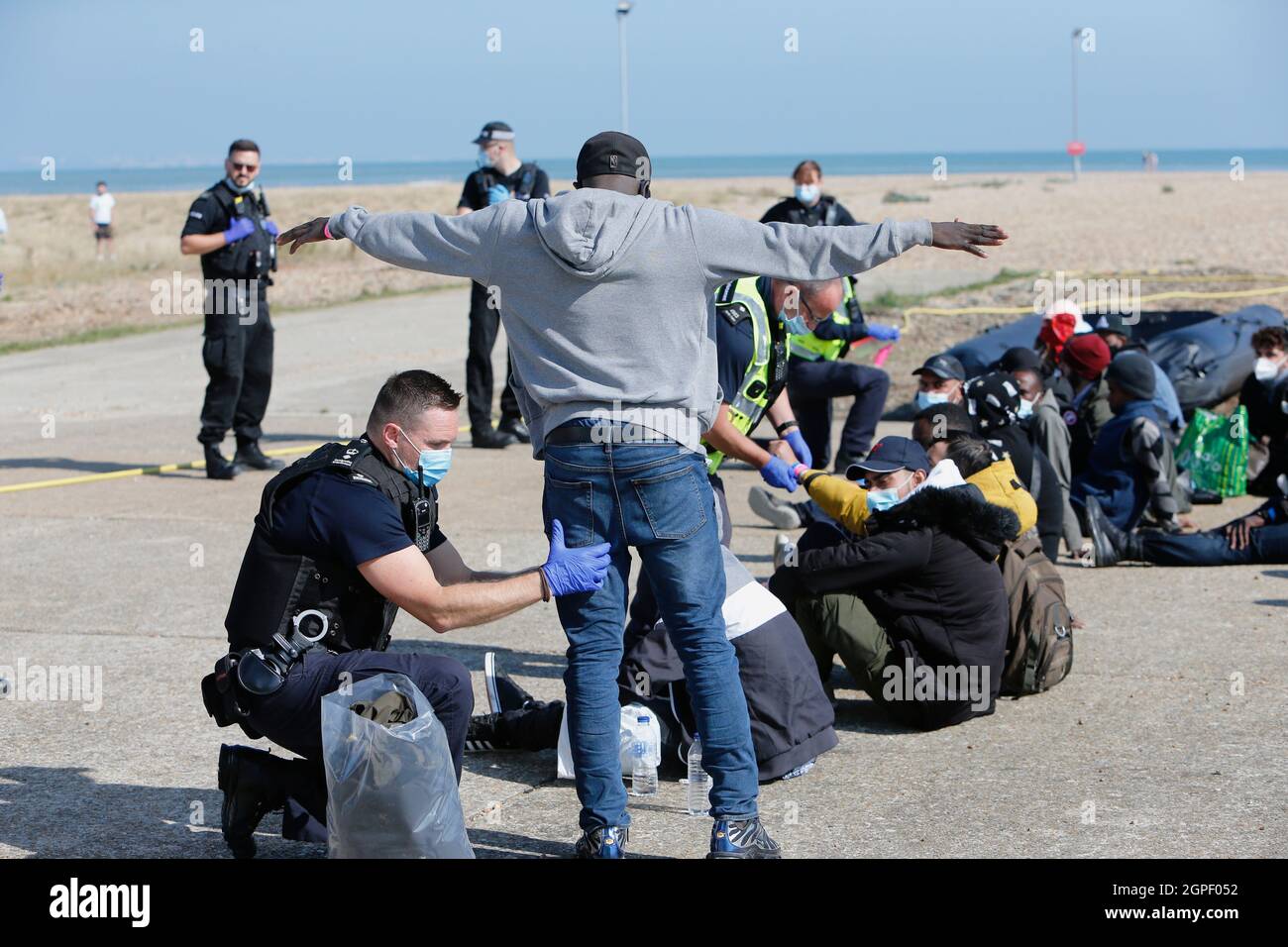 England, Kent, Dungeness, Migrants being searched by immiragtion officers on the beach. Stock Photo