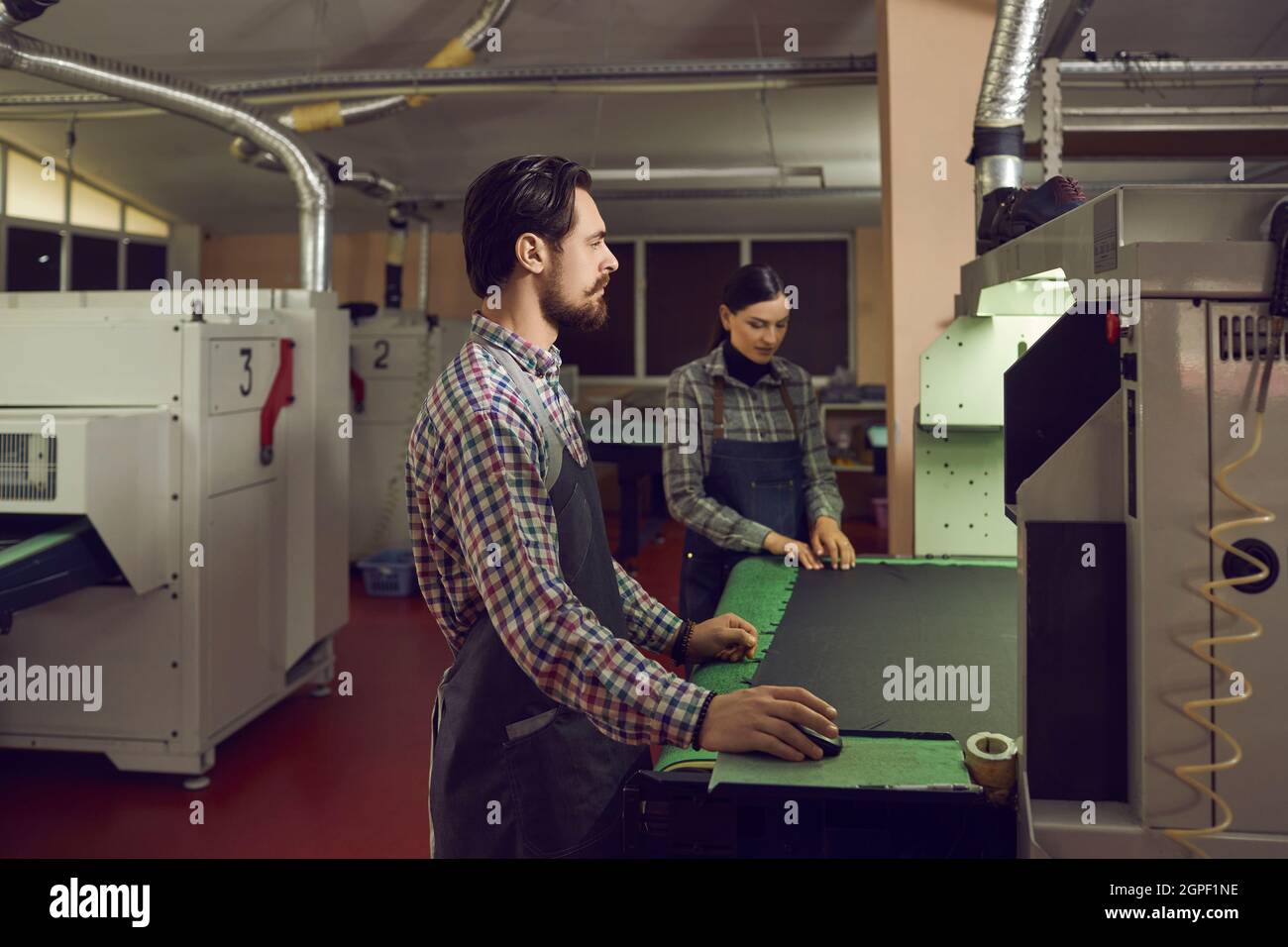 Shoe factory workers working with a cutting machine at a footwear