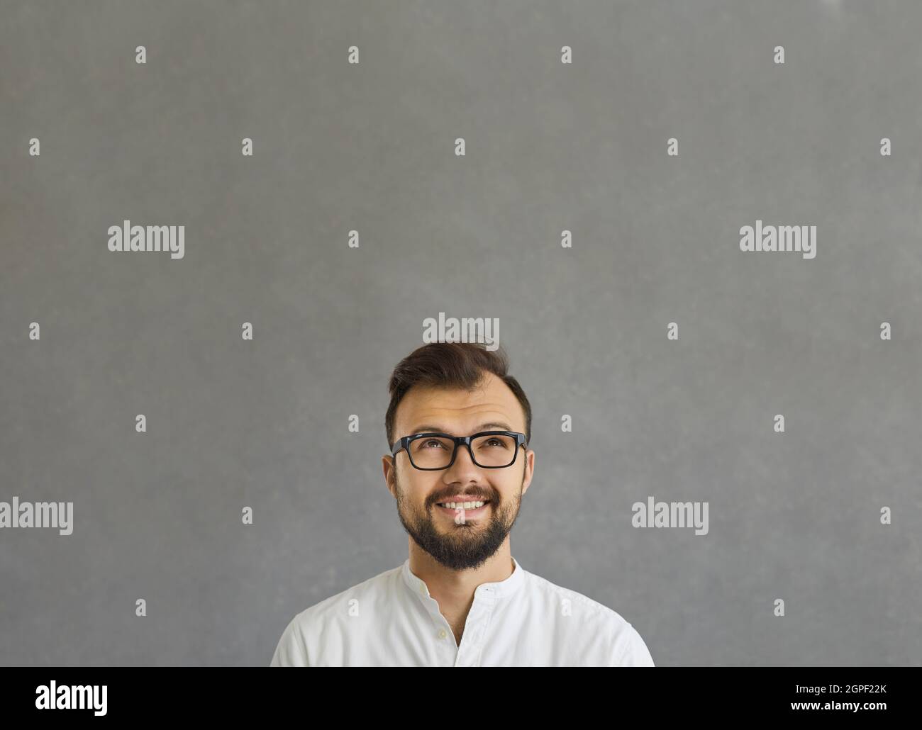 Close up portrait of thoughtful young pensive businessman looking up on grey Stock Photo