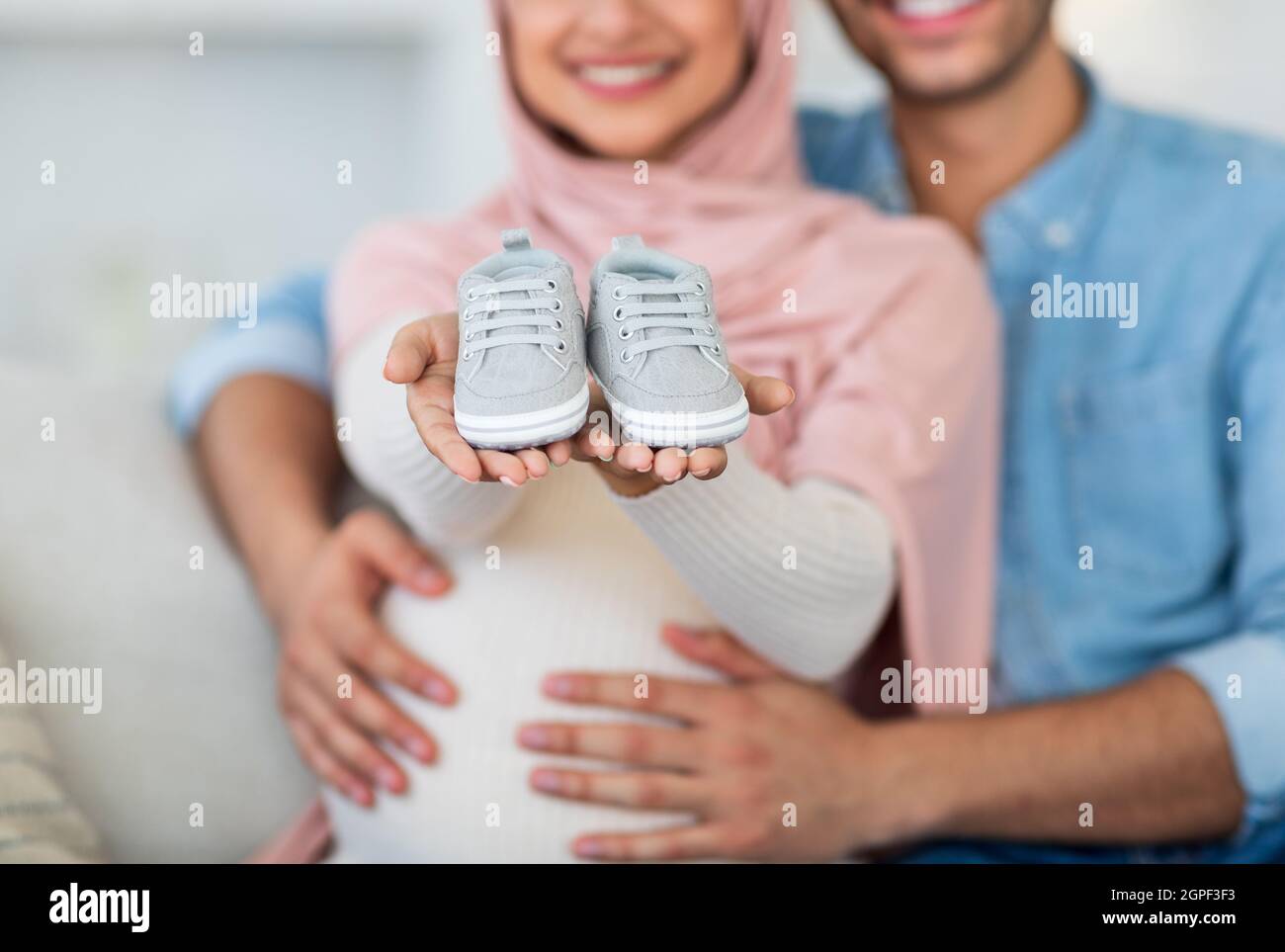 Parenthood concept. Cute baby shoes in pregnant muslim couple ...