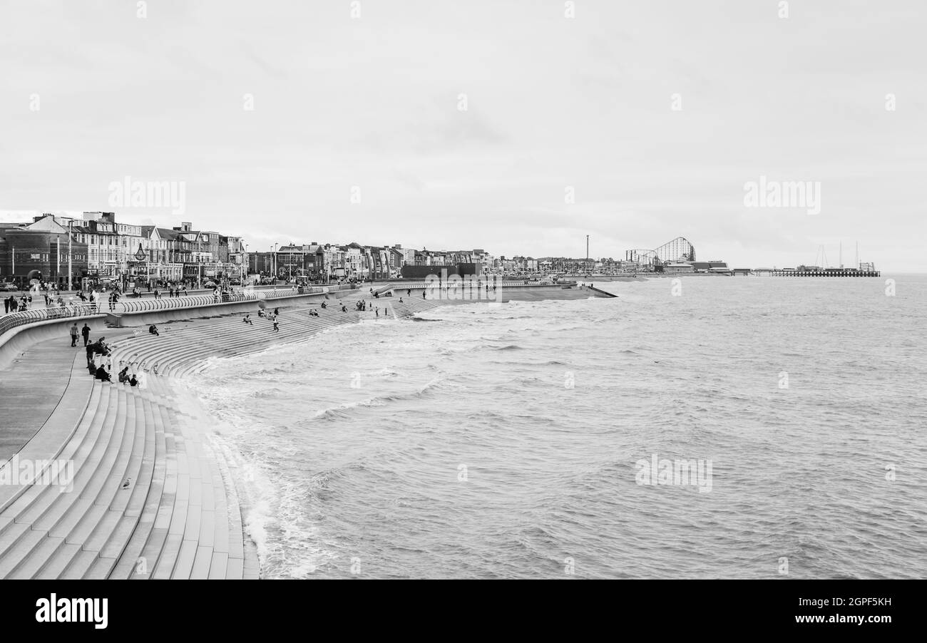 Tourists seen dotted along the Blackpool beach South promenade seen in black and white during September 2021. Stock Photo