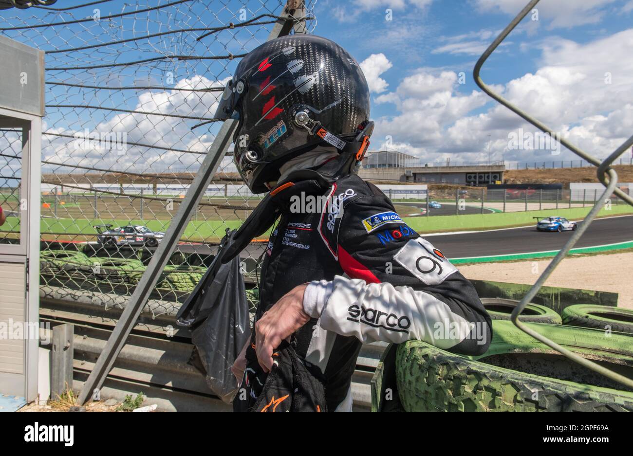 Vallelunga, italy september 19th 2021 Aci racing weekend. Car driver in helmet and racing suit out of race looking at cars on track behind safety barr Stock Photo
