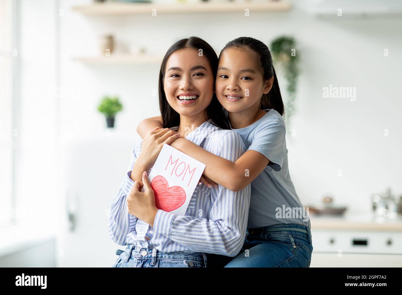 https://c8.alamy.com/comp/2GPF7A2/pretty-asian-girl-greeting-mom-with-mothers-day-daughter-with-handmade-gift-card-embracing-her-mother-from-back-2GPF7A2.jpg