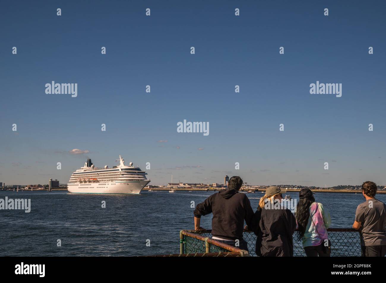 Boston, MA, US - September 19, 2021: People watch as nearly empty cruise ship leaves harbor. The cruise industry has struggled economically during the Stock Photo