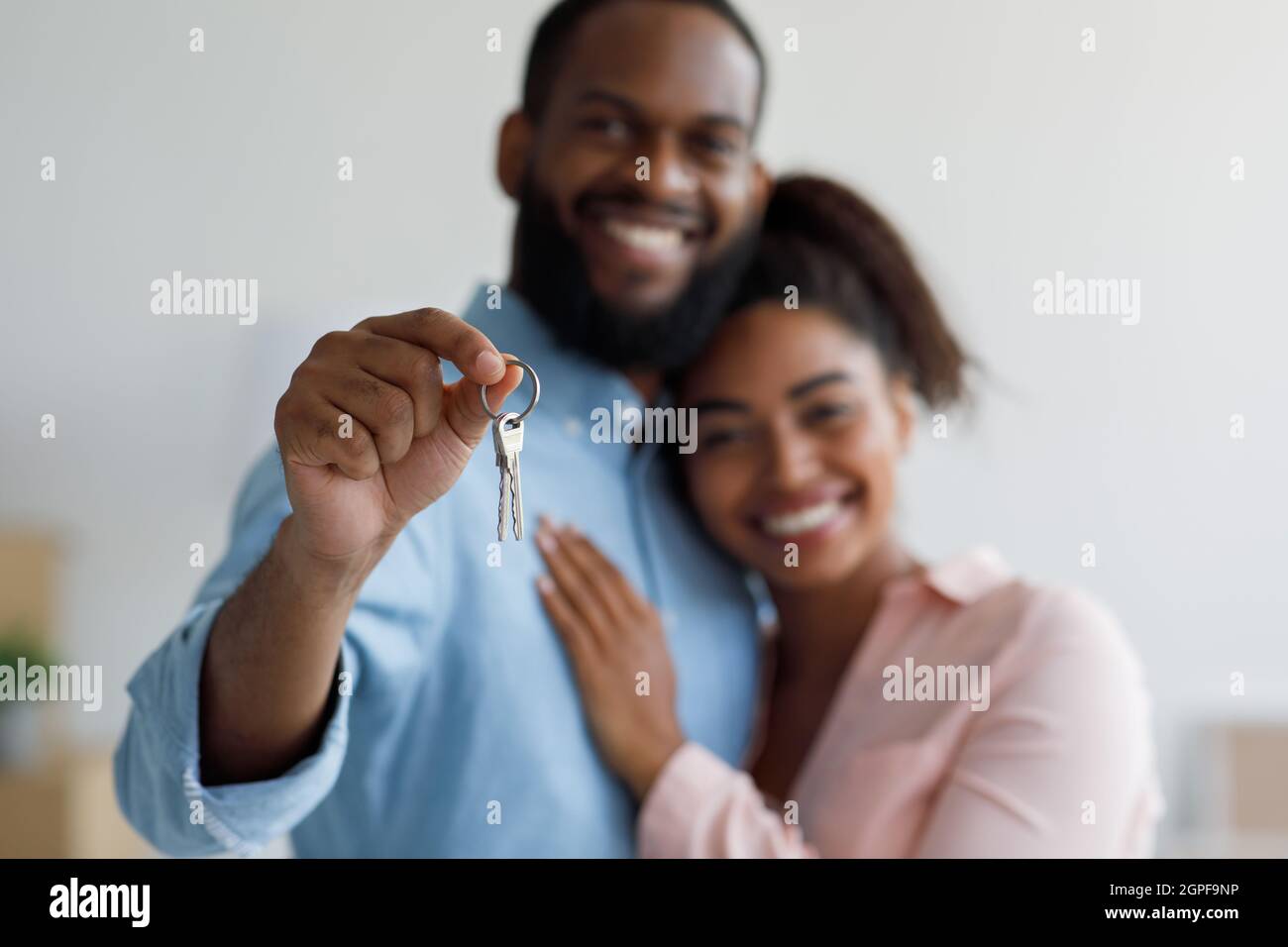 Smiling young afro american couple hugging and show keys to new ...