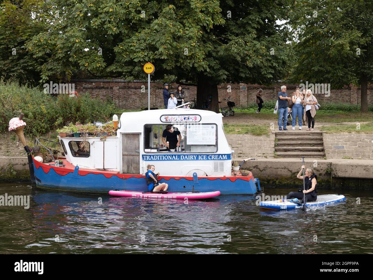People buying ice cream in their canoes from an ice cream boat on the