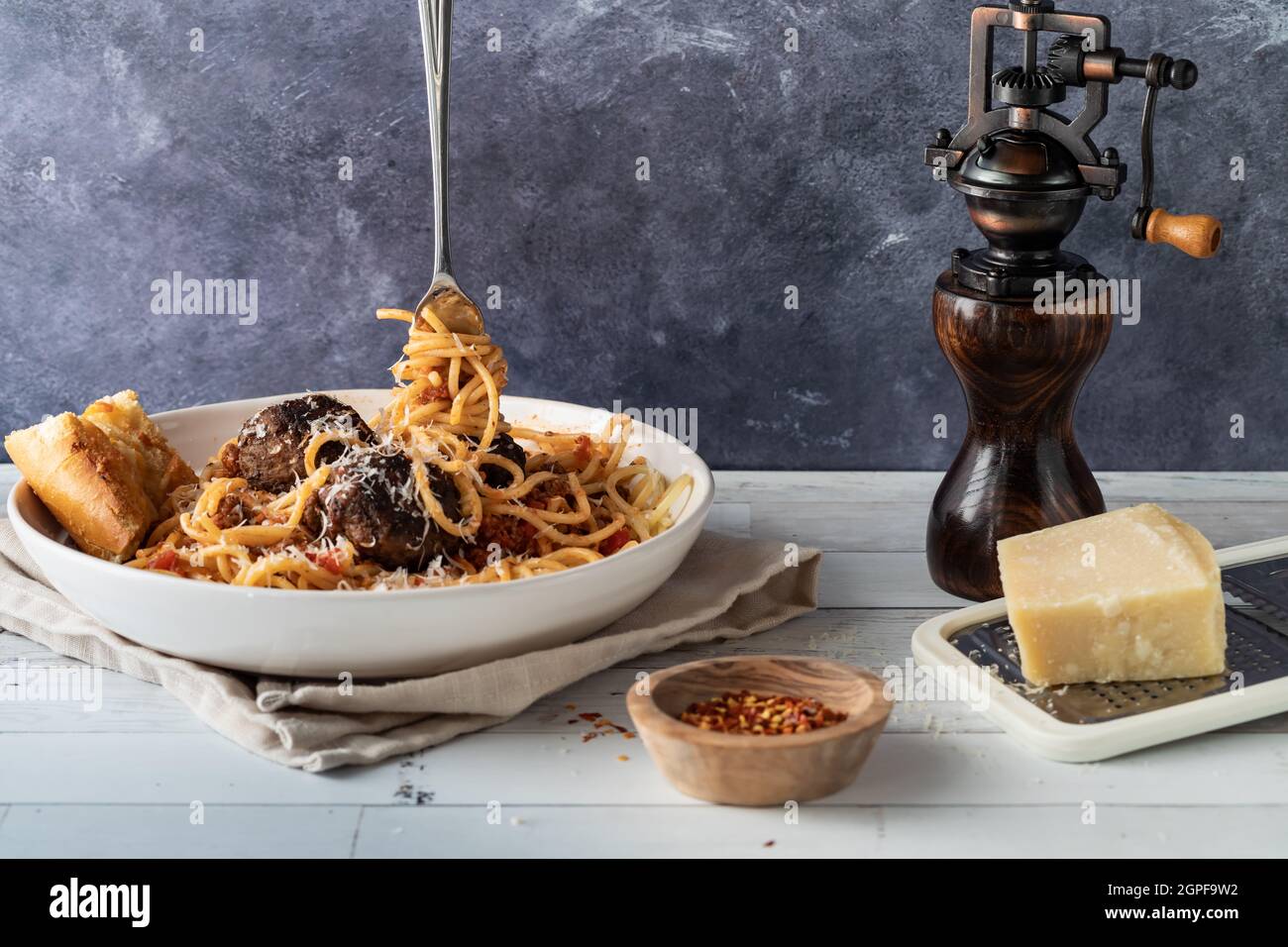 A dish of spaghetti and meatballs with a fork full of noodles standing