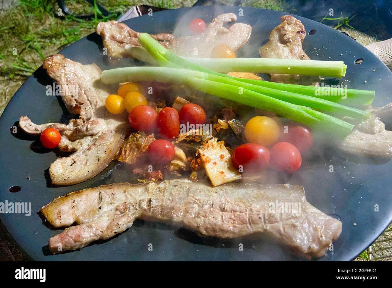 cooking pork belly and vegetables at the campsite Stock Photo