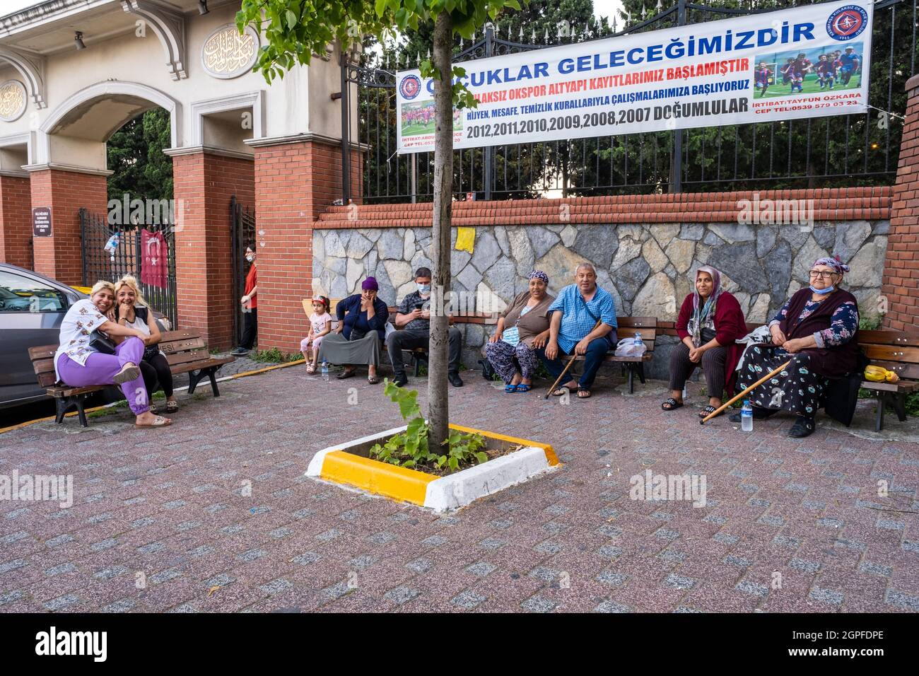 Beyoglu, Istanbul, Turkey - 06.27.2021: a lot of happy Turkish Romany Gypsy citizens and family sitting on public benches and looking at camera and po Stock Photo