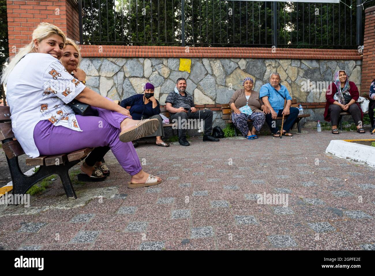 Beyoglu, Istanbul, Turkey - 06.27.2021: a group of cheerful Turkish Romany Gypsy people sits on several public benches and looking at camera and posin Stock Photo