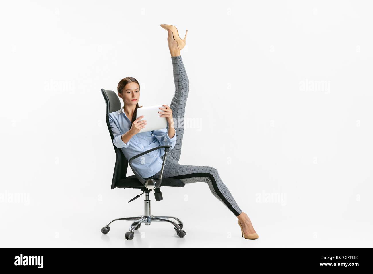 Portrait of woman, office worker standing on chair in ballet pose and