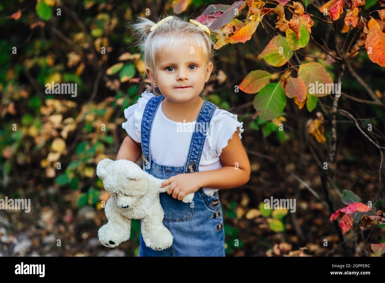 Little white girl in a white blue dress laughs in forest. Preschooler ...