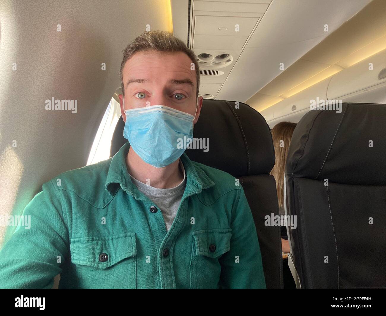 A young man wearing a protective mask on an airplane flight Stock Photo