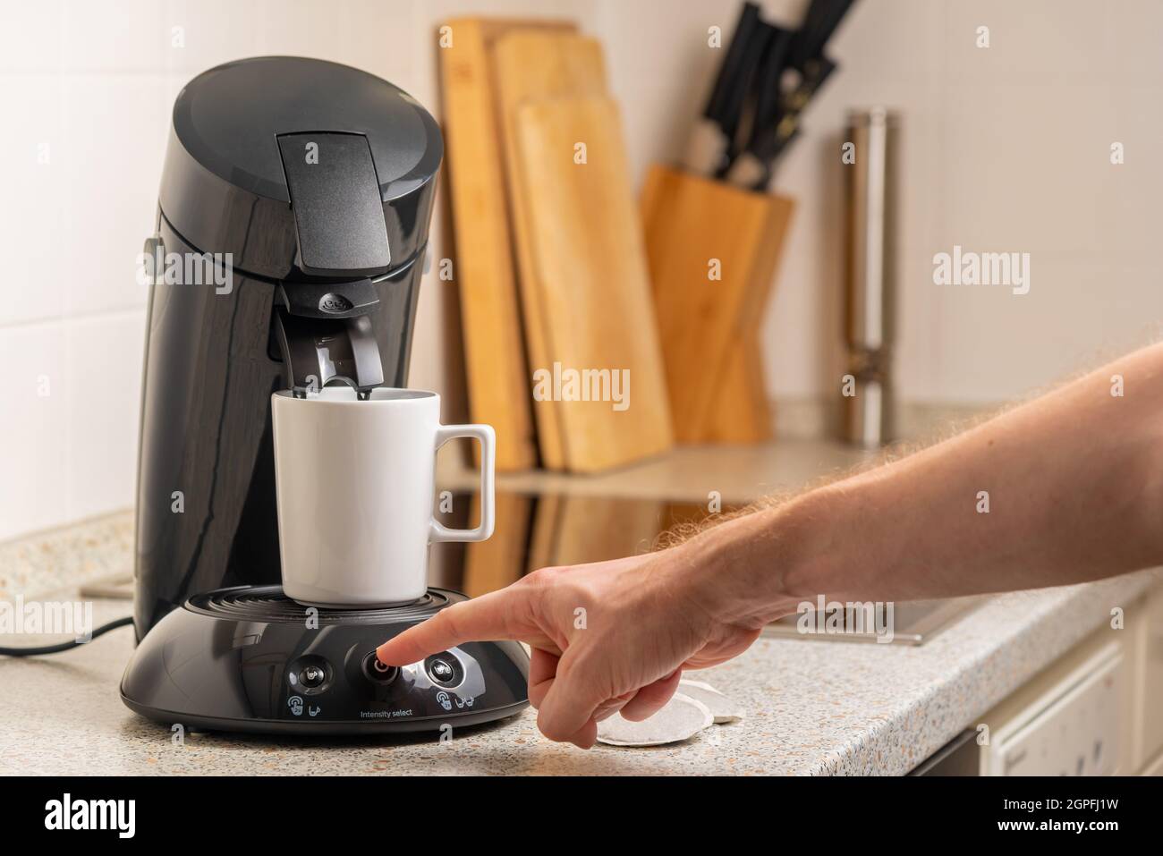 Male hand pressing the power button on the coffee maker in the kitchen. High quality photo Stock Photo