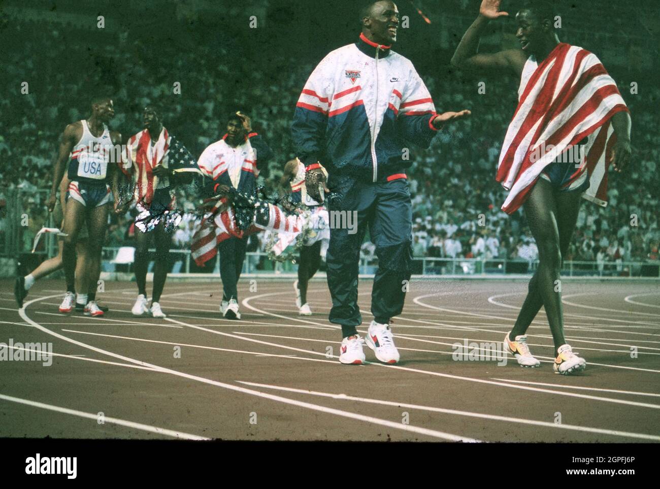 Barcelona Spain, 1992: Members of the United States men's  4X400-meter relay relay team take a victory lap around the track after setting a world record in the event before a packed stadium during the Summer Olympic Games. ©Bob Daemmrich Stock Photo