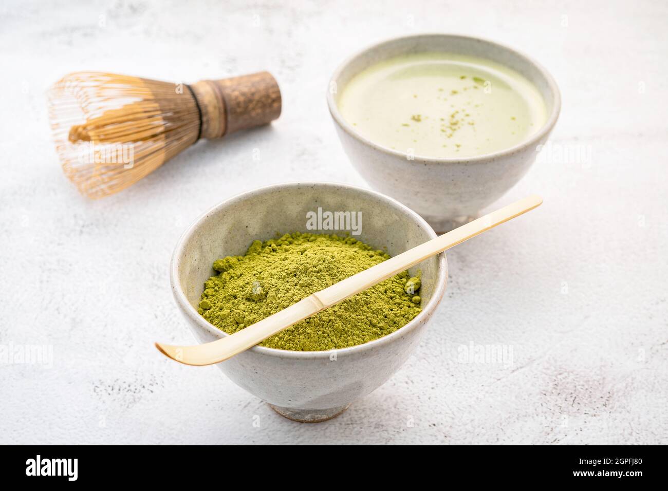 Matcha green tea powder with bamboo matcha whisk brush setup on white