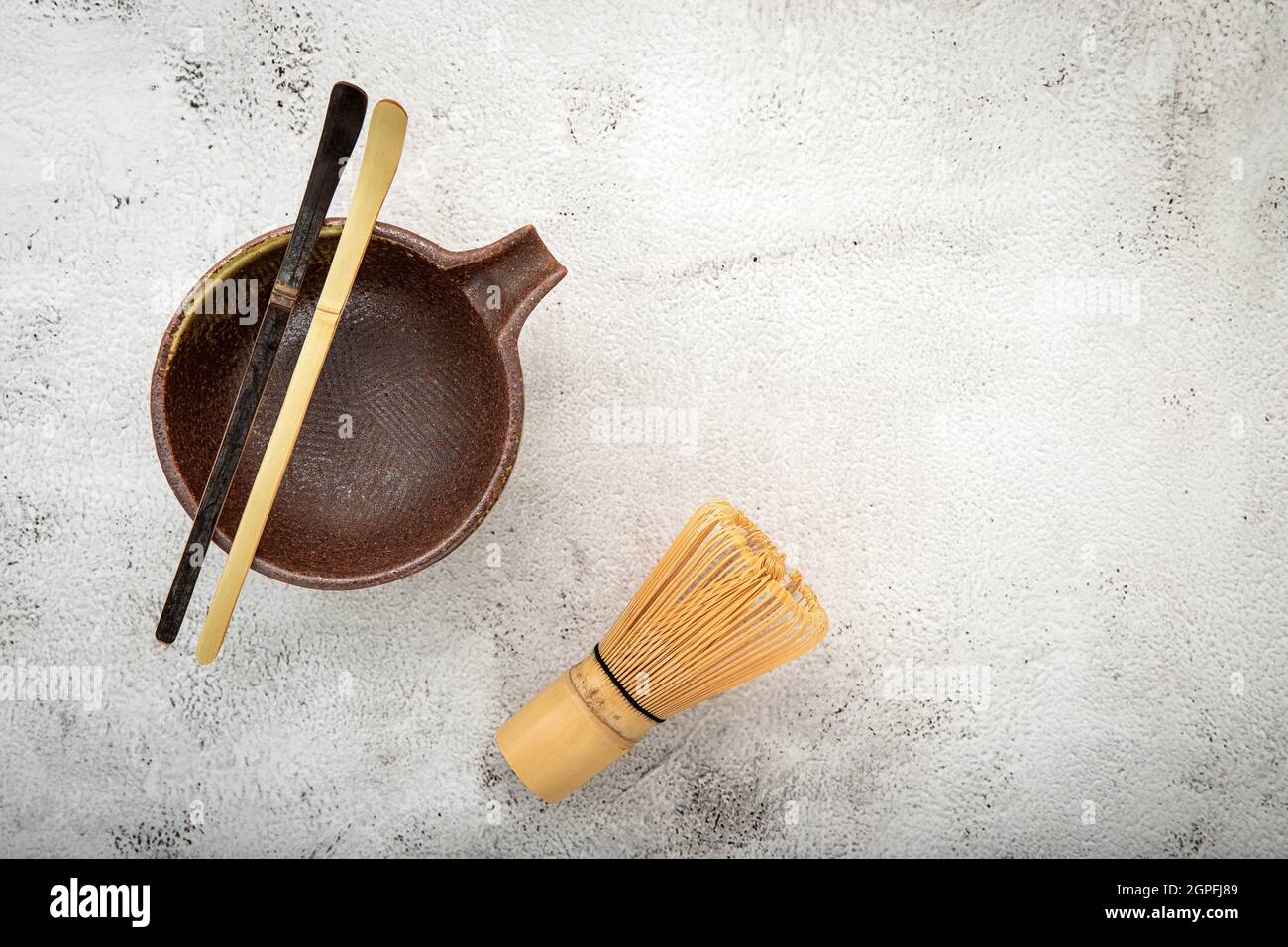 Matcha set bamboo matcha whisk and chashaku tea scoop,matcha ceramic bowl set up on white concrete background. Stock Photo