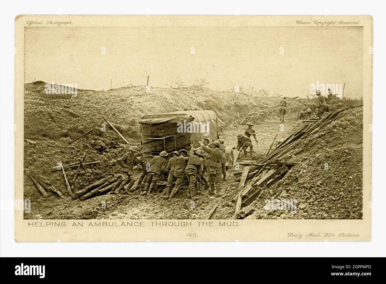 Original WW1 era Daily Mail War Pictures postcard of soldiers helping push an ambulance belonging to the 16th (Irish) Division through the mud in Mametz Wood, Battle of the Somme, France, July 1916. Official War Photographs series. Printed in England. Stock Photo