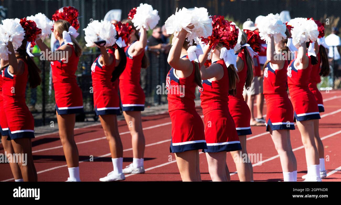 High school cheerleaders holding their pompoms in the air while
