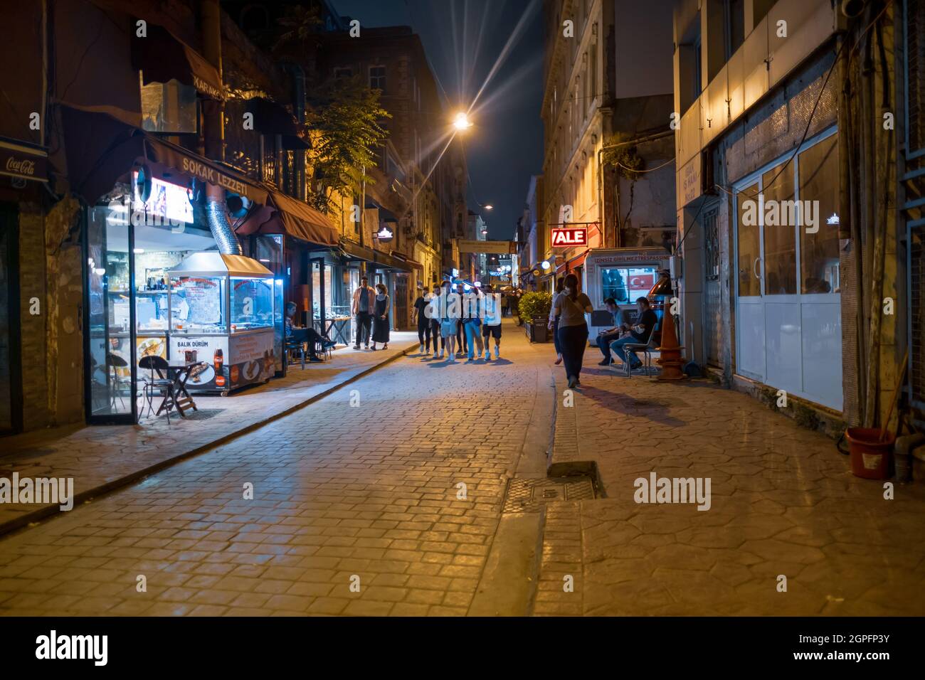 Beyoglu, Istanbul, Turkey - 07.07.2021: Karakoy street and small shops with shiny lights at night time and some people tourists walking around for tra Stock Photo