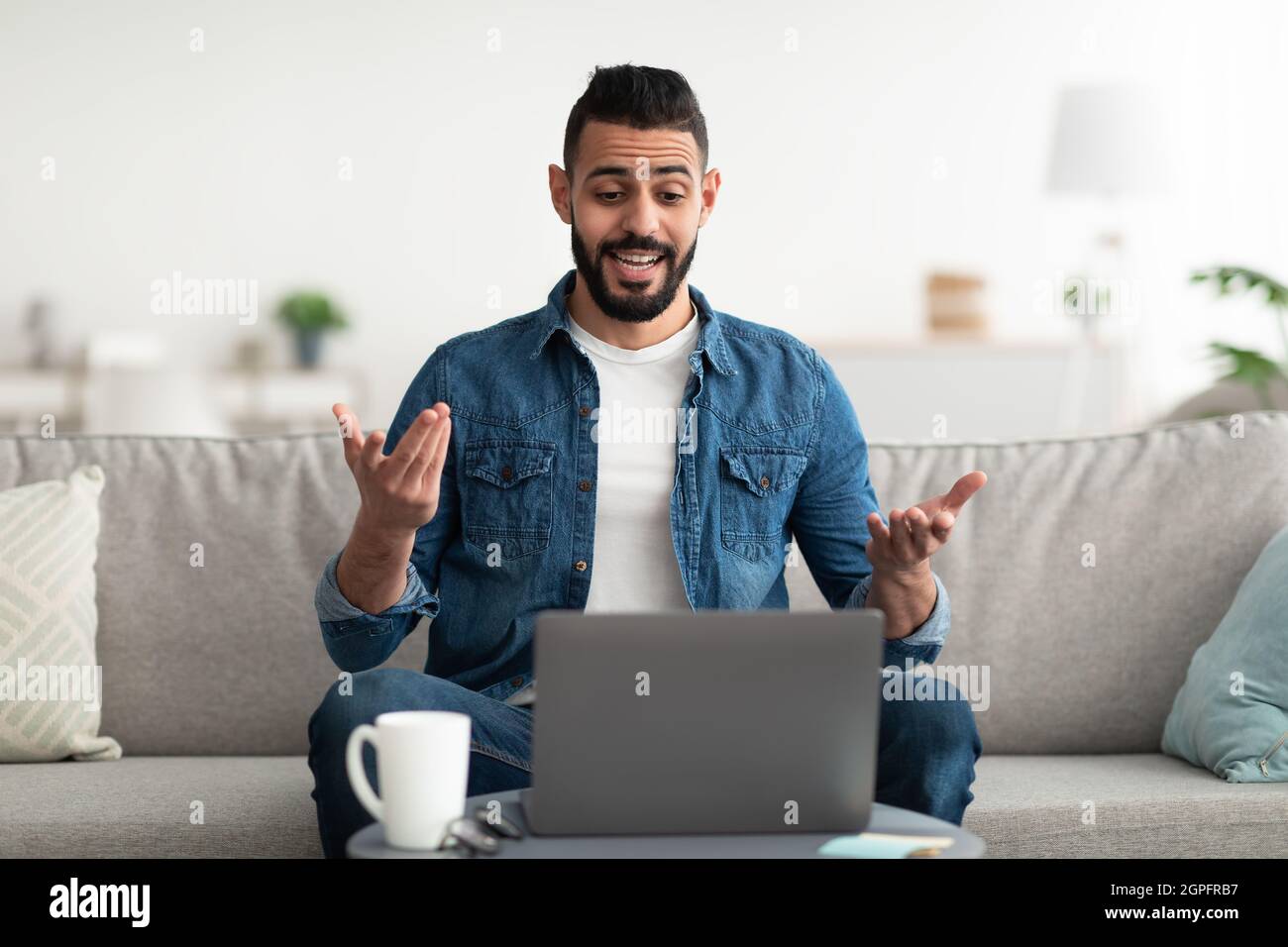 Distance communications. Young Arab guy having video call on laptop from home office, discussing work issues remotely Stock Photo
