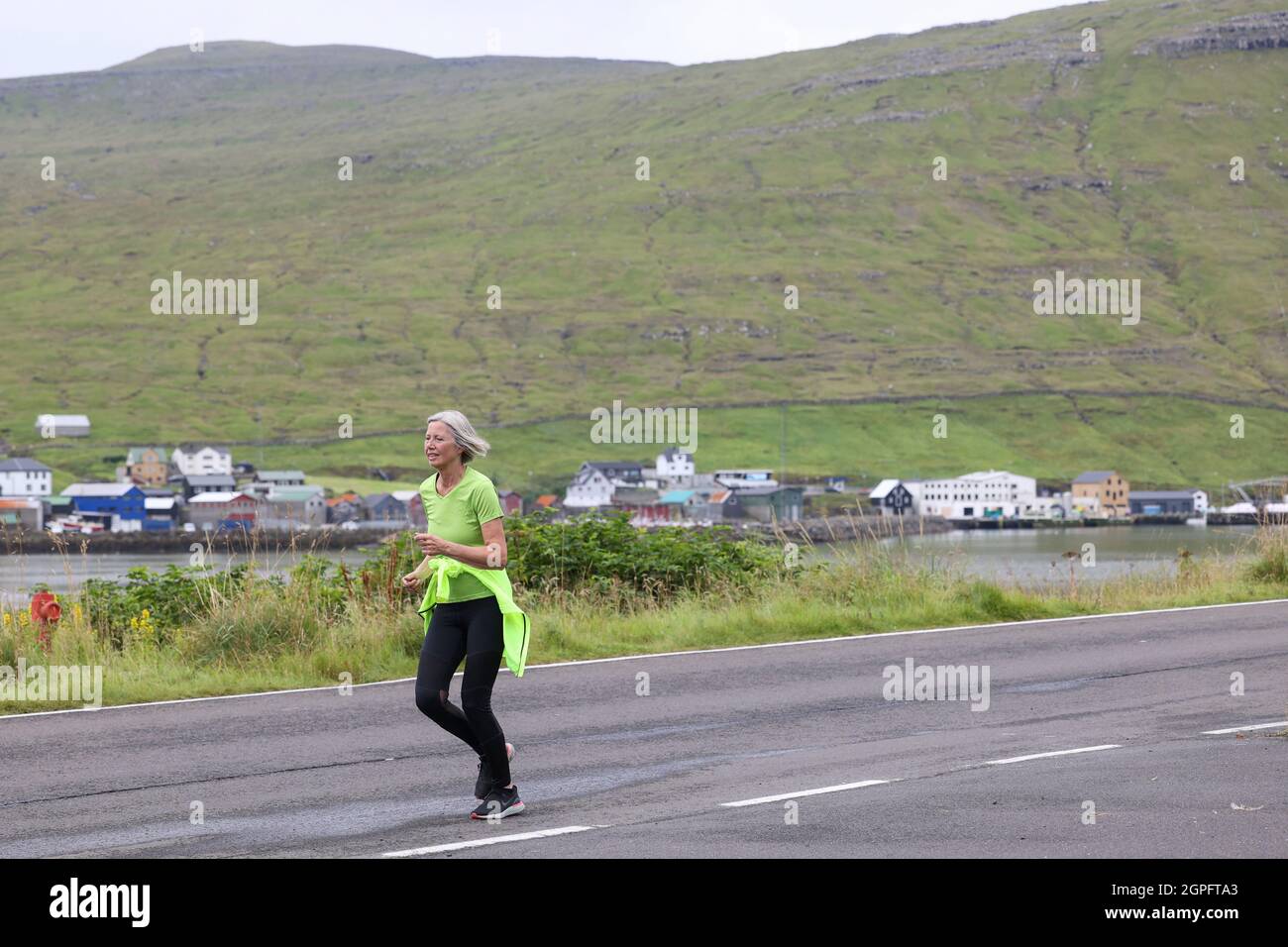 Female runner participating in the half marathon from Gasadalur to Sandav‡gur, Vagar Island, Faroe Islands, Europe. Stock Photo