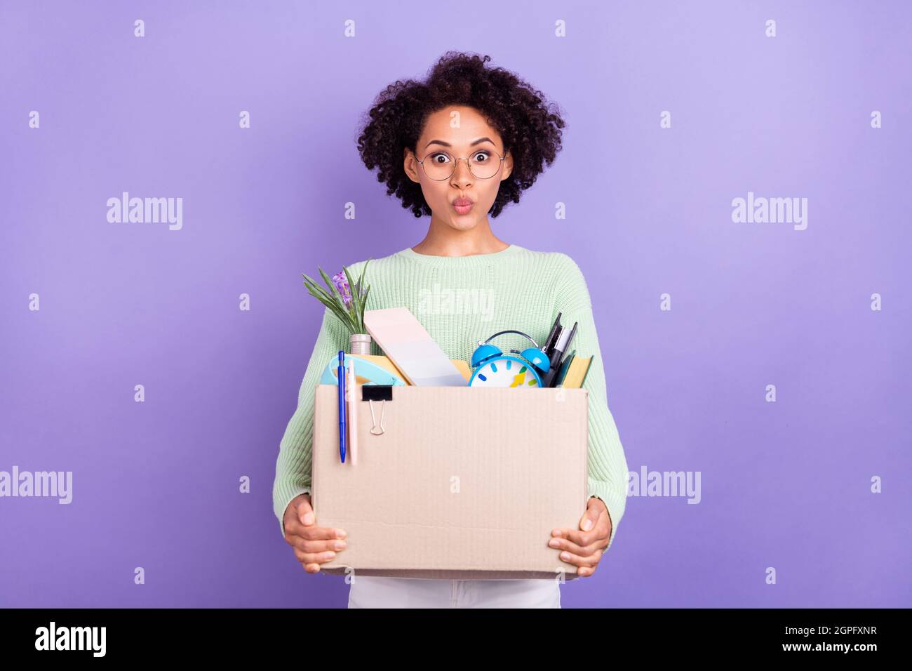 Photo of young amazed dark skin shocked woman hold hands box college move isolated on violet color background Stock Photo