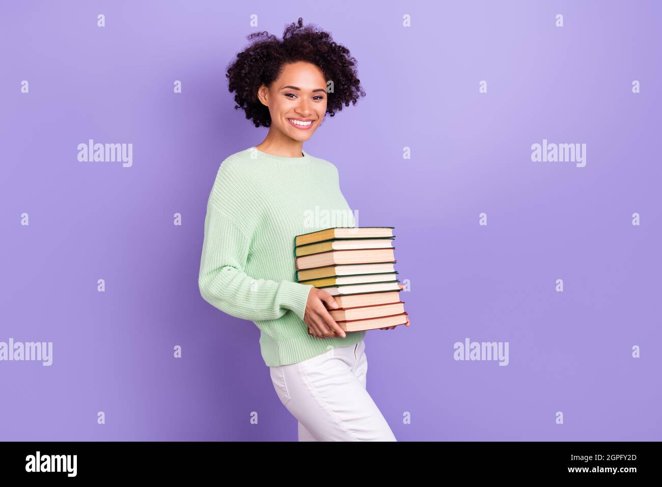 Photo of cheerful happy joyful dark skin woman smile good mood hold hands books isolated on purple color background Stock Photo