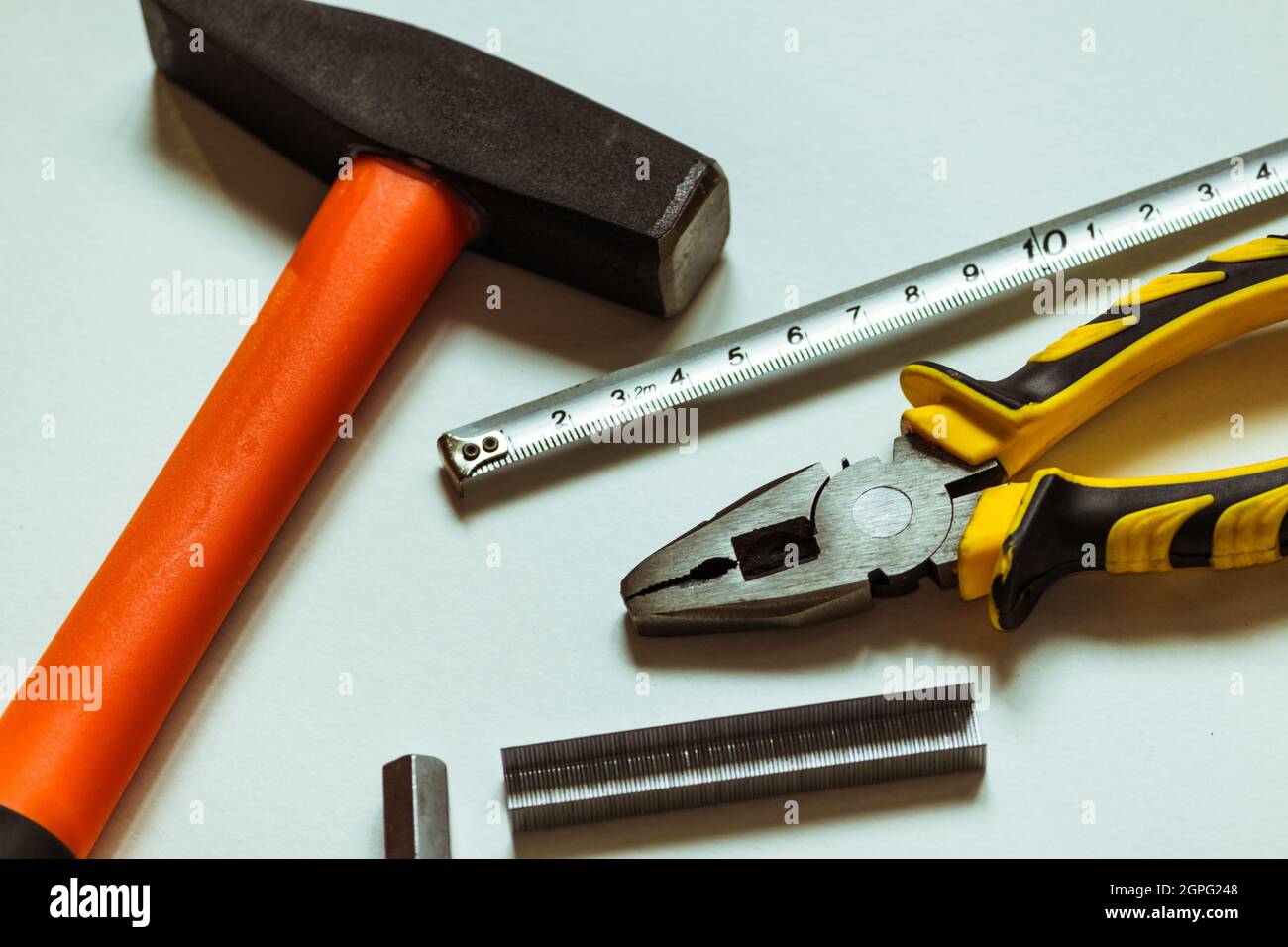 A set of metal hex keys next to a hammer, pliers and a tape measure. Stock Photo